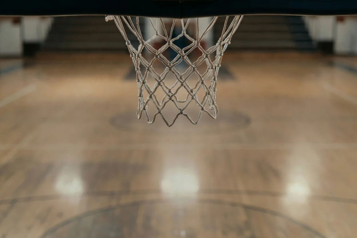 Boş basketbol sahasında pota filesi yakın çekim, sıcak salon ışıkları