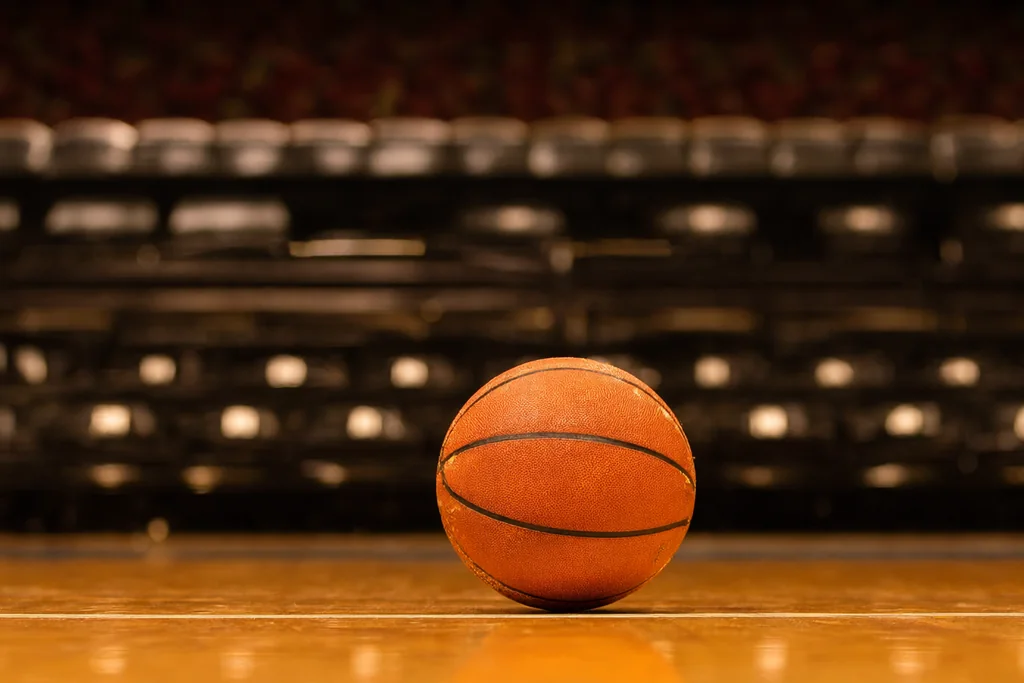 Parke zemin üzerinde yan yana dizilmiş turuncu basketbol topları, salon ışığı