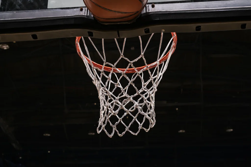 Boş kapalı salon basketbol sahasında pota, pano ve file, alttan çekim